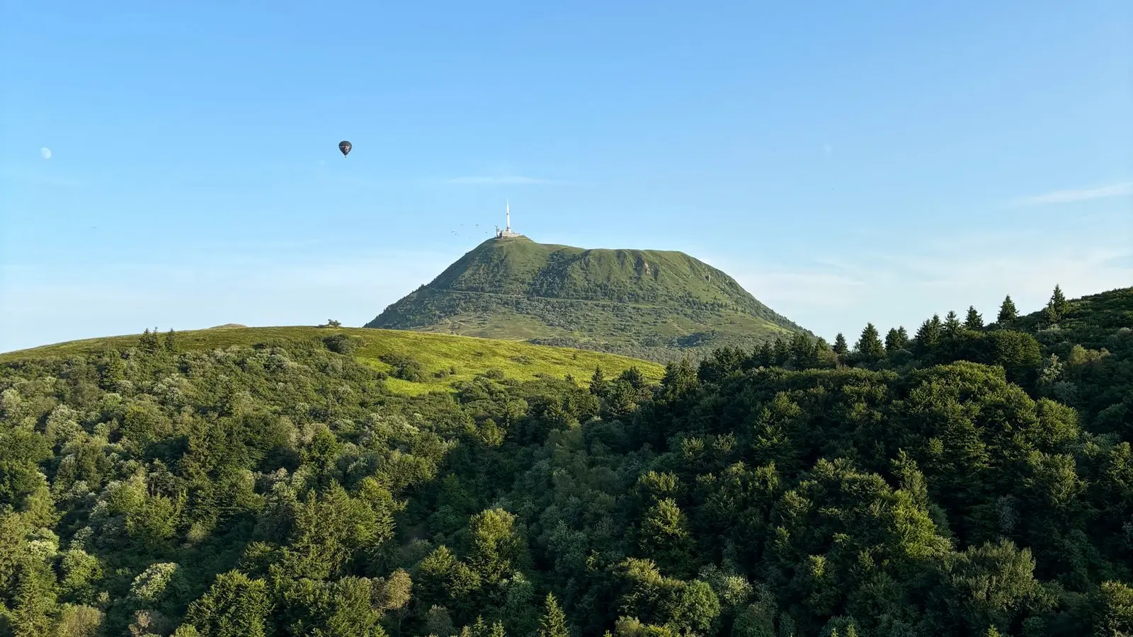 Le puy de Dôme vu depuis la chaîne des Puys, avec une montgolfière dans le ciel