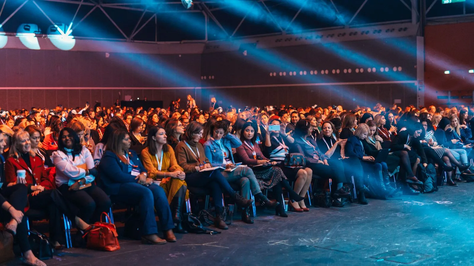 Large audience réunie dans une salle de conférence sous les éclairages de scène